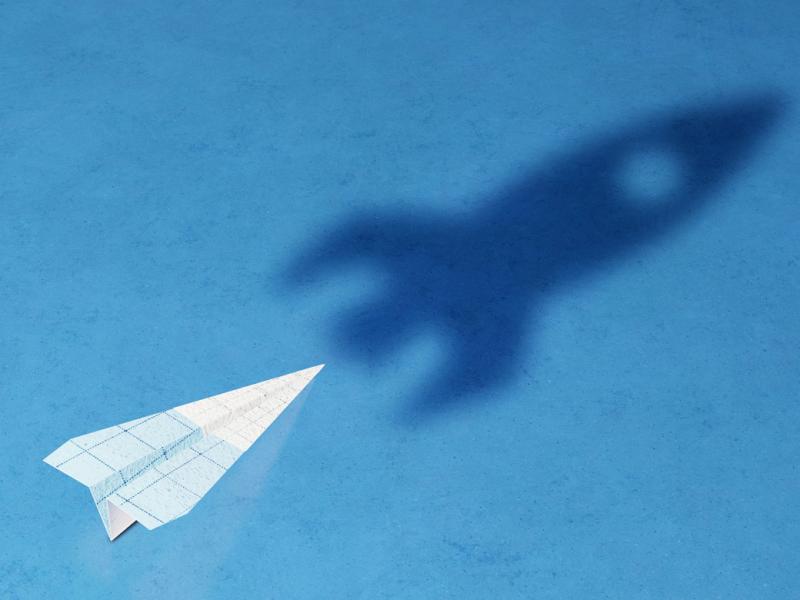 Paper airplane in the shadow of a rocket