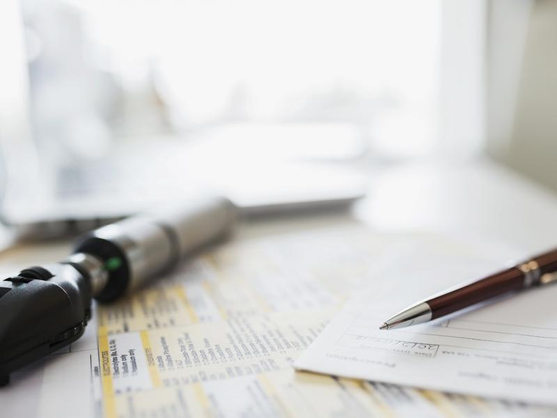Physician's desk with otoscope and paperwork