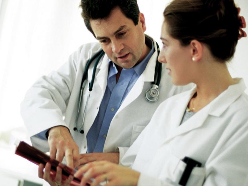 A man and a female physician look at the screen of a tablet.