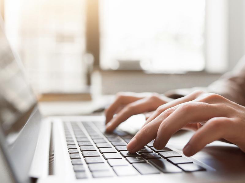 Close up of hands using a laptop.