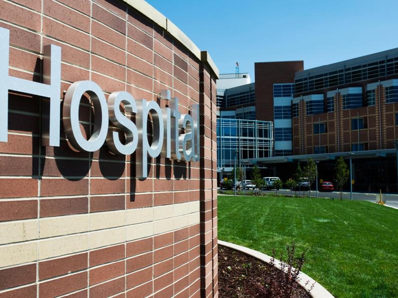 The brick side of hospital building with a metal sign spelling the word, Hospital.