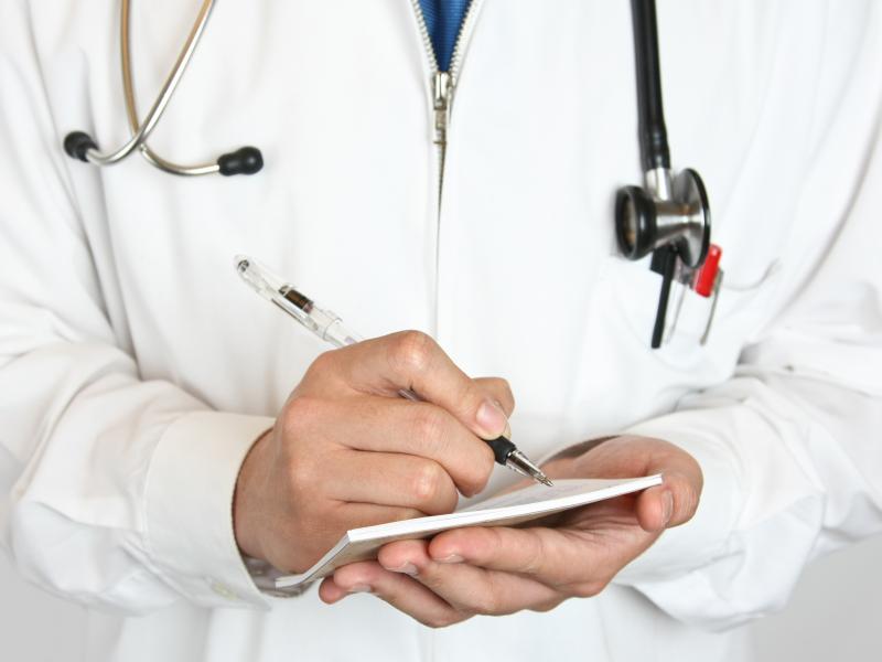 Physician writing on a prescription tablet