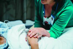 A woman's hand placed over the hand of a patient