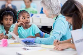 Older female physican attends to young patients
