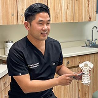 Daniel E. Choi, MD, pointing to spine vertebrae model
