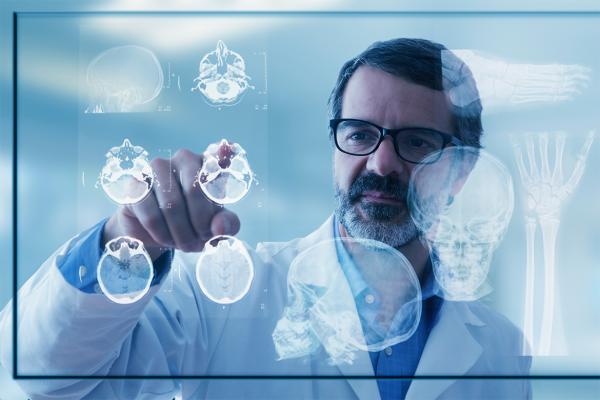 Physician pointing to augmented intelligence (AI) screen displaying brain.