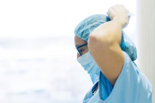 Health care professional tying mask around face