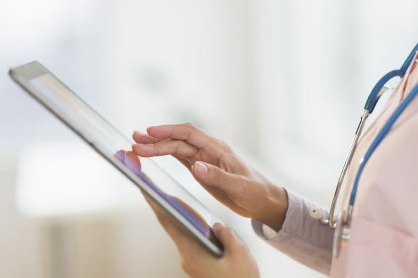 Close-up photo of a physician using a smart tablet.
