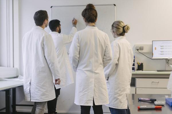 Group of med students and teacher standing in a classroom
