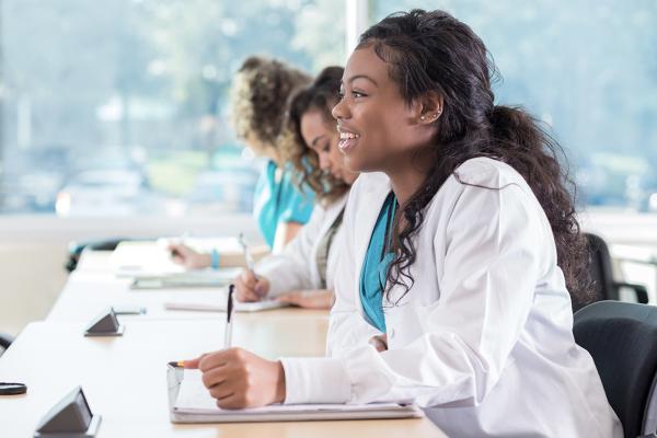 A medical student smiles as she takes notes in class.