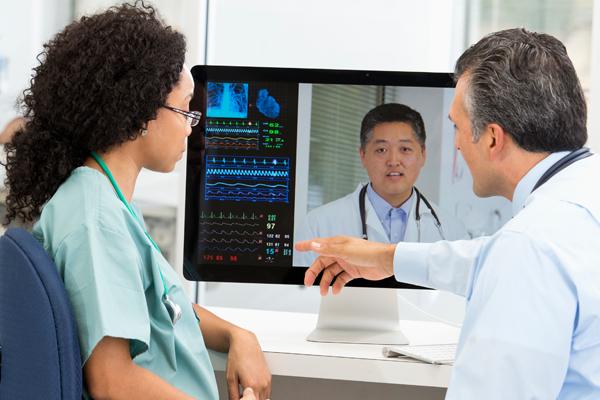 A male and female physician in front of a computer monitor.