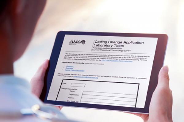 A physician holds a tablet, which displays the AMA Coding Change Application.