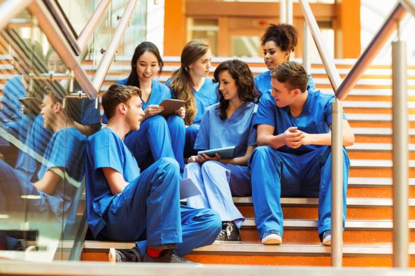 Group of medical school students in blue scrubs, sitting on the stairs
