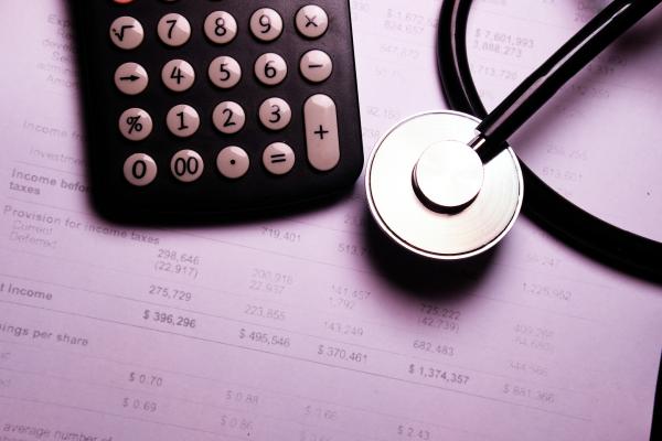 A stethoscope and calculator sit on top of a medical billing statement.