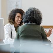 Female physician speaking to seated female patient