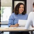 Office manager holds a document while speaking with a person across the table