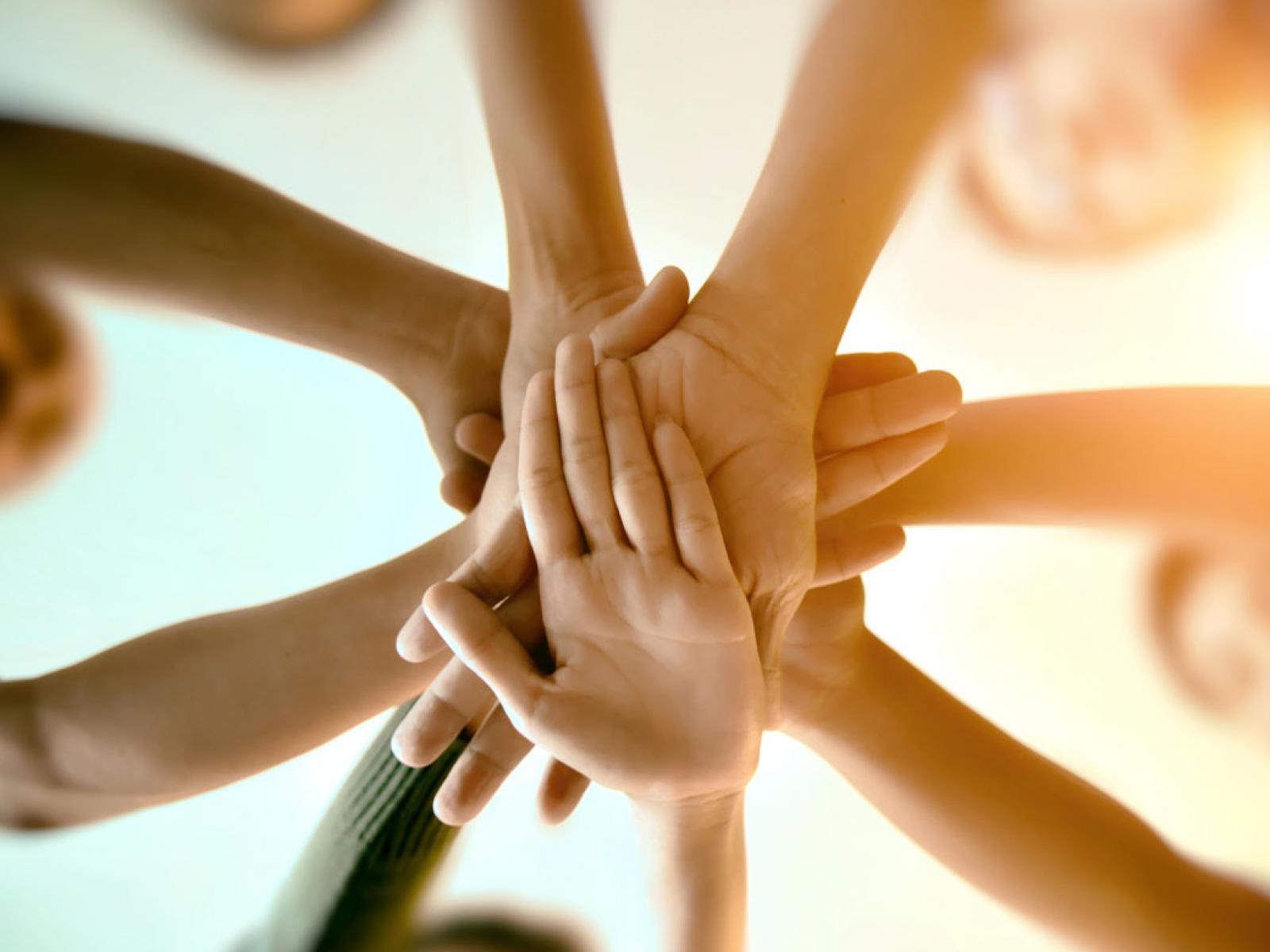 Several people putting their hands together