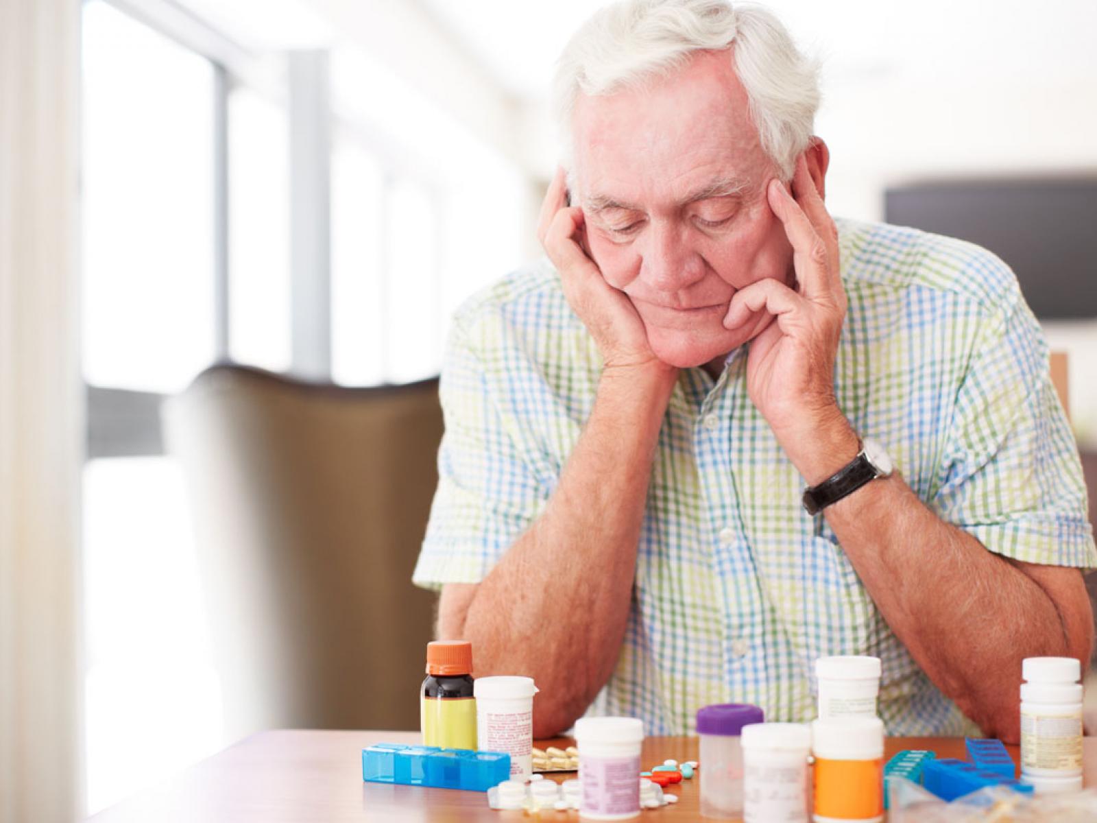 Elderly man looking at prescription bottles