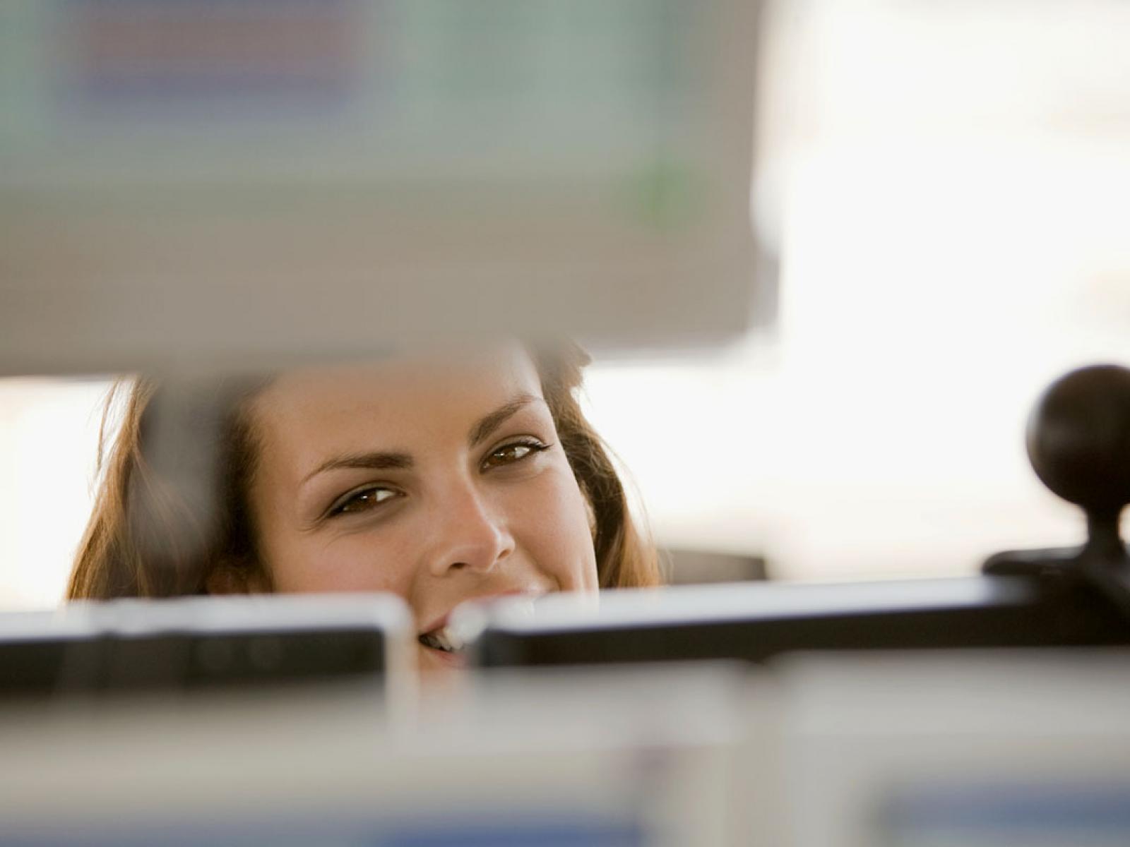 Smiling person behind a computer screen
