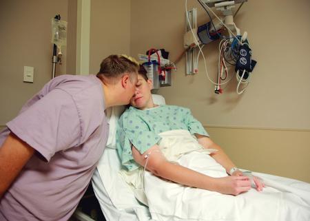Patient on hospital stretcher being comforted by another person