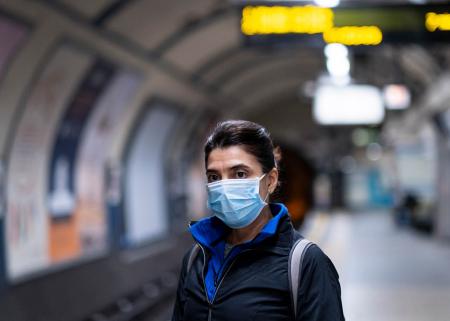 Person wearing facemask in an empty underground train station