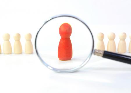 Illustration of a magnifying glass looking at beige game pieces with the focus on a single red game piece