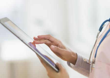 Close-up photo of a physician using a smart tablet.