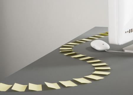 Trail of sticky-notes in an s-curve pattern leading to a computer.