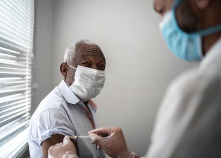 Elderly man receiving vaccine from physician