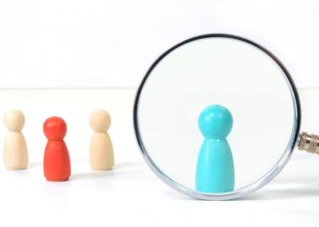 Different colors of figurines with one under a magnifying glass