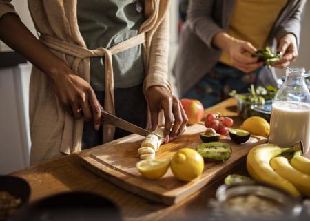 People cutting fruit in a kitchen