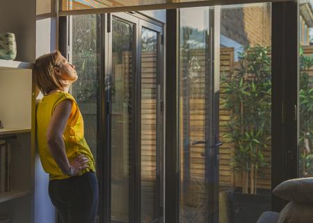 Person with eyes closed, leaning against a bookshelf