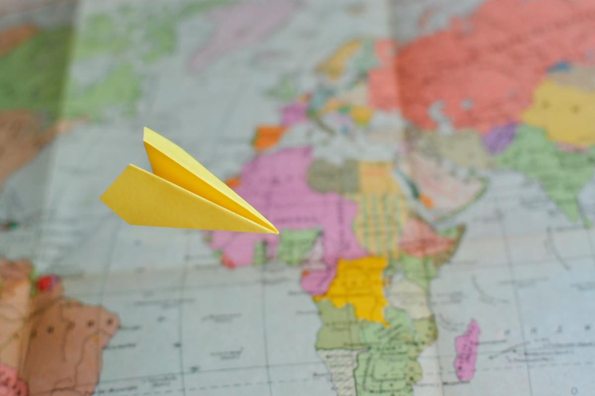 Map with a paper airplane flying in front of it