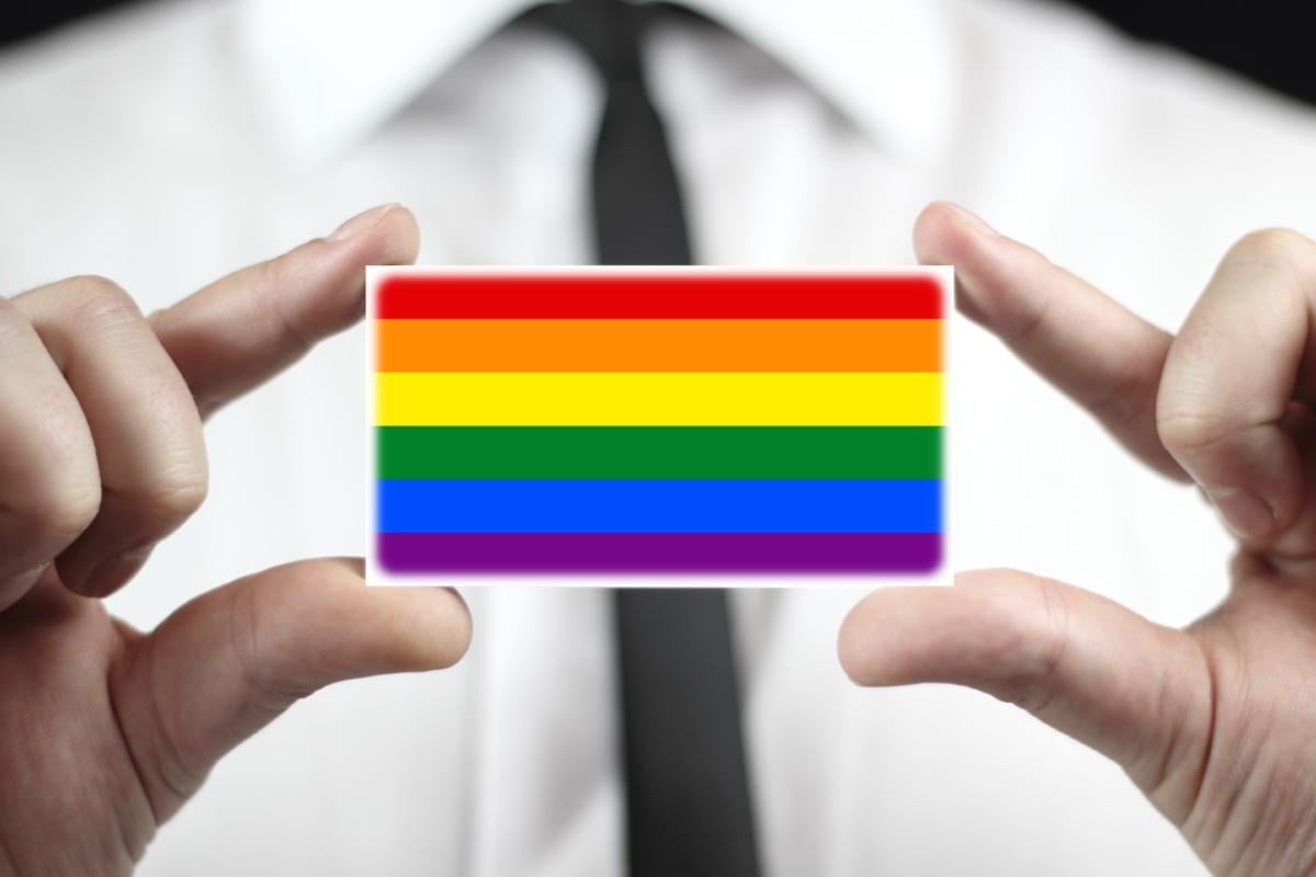 A close-up photo of a person holding a business card size rainbow.