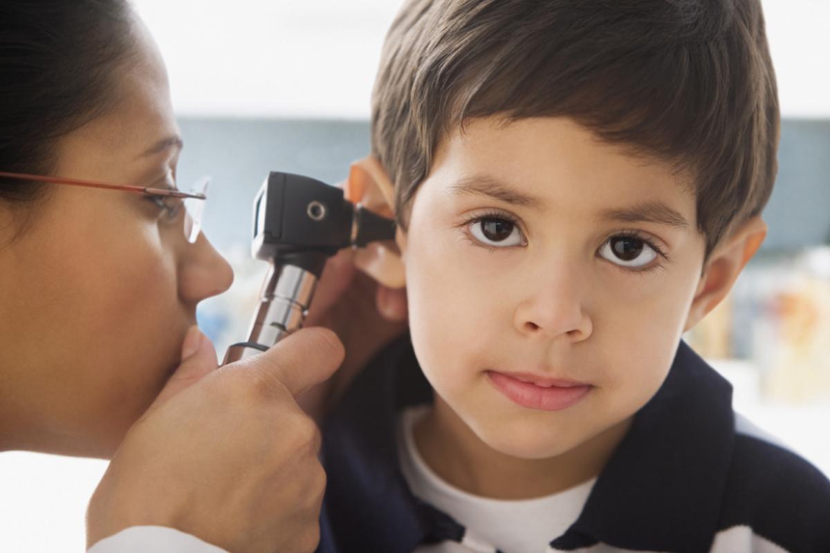 Doctor looking to child's ear with an otoscope