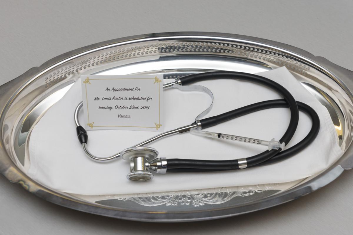 Stethoscope and syringe sitting on a platter with a note