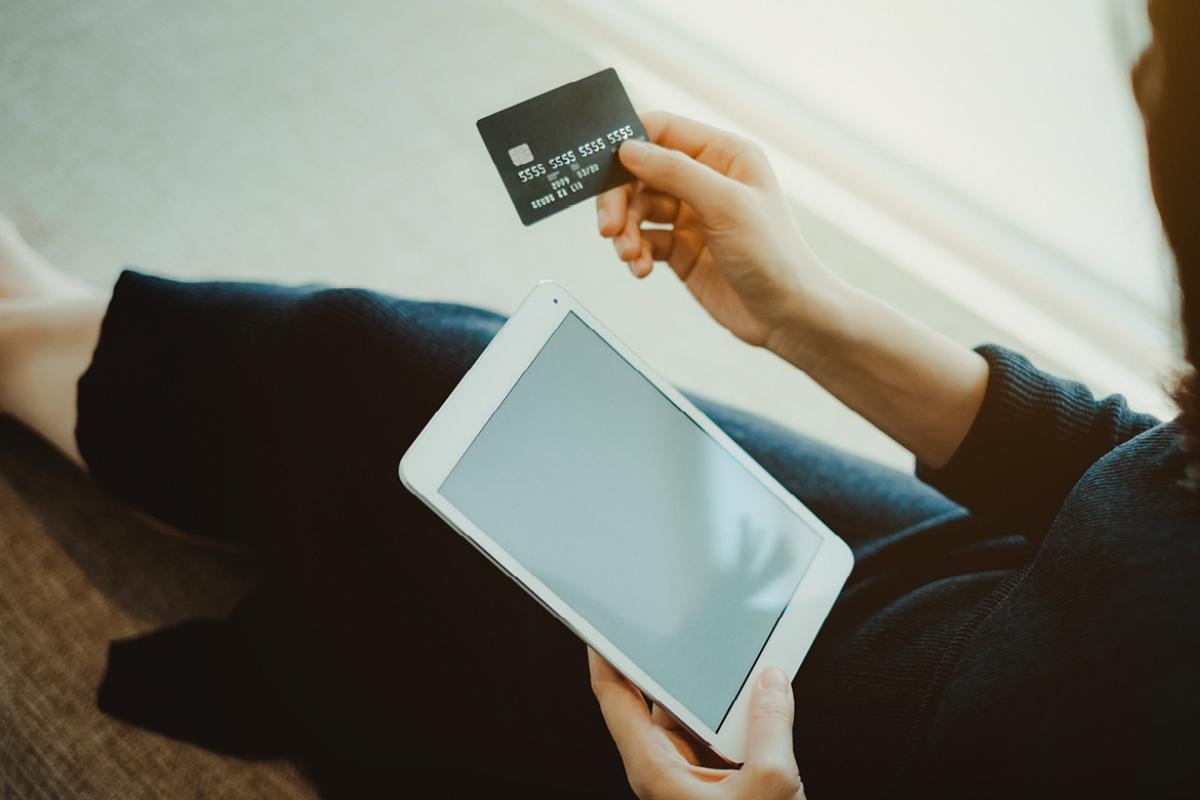 Person holding credit card and tablet computer