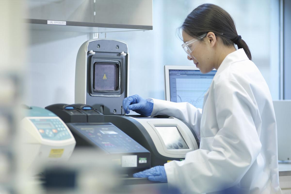Woman in lab coat at testing machine