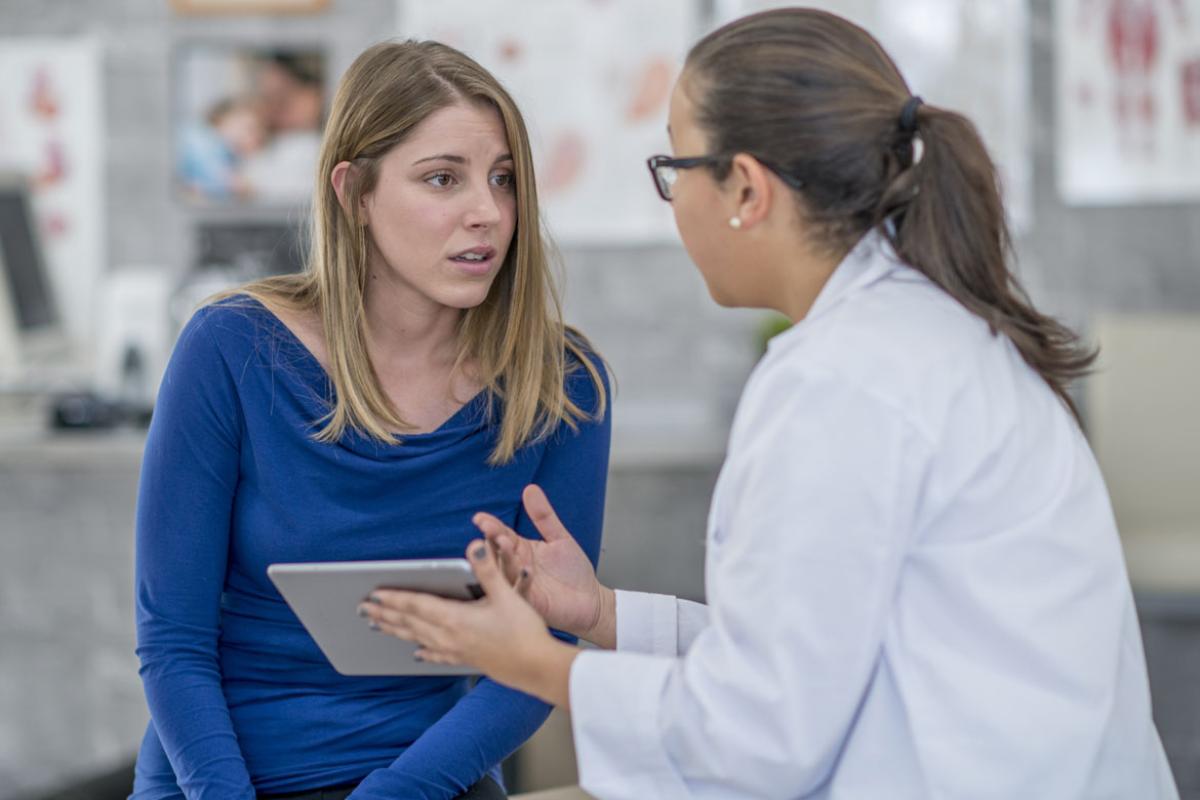 Female physician holding a tablet and speaking to a young woman