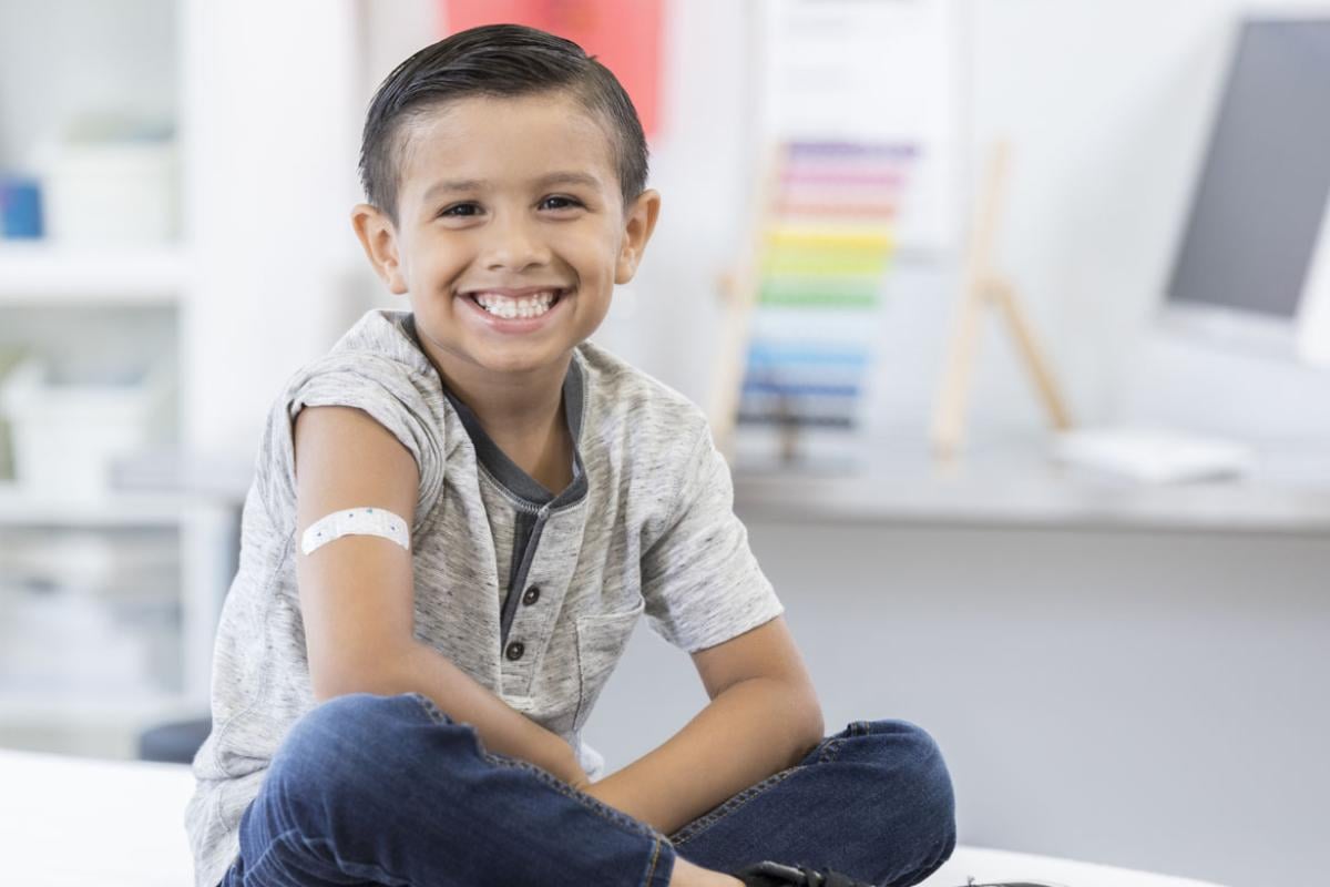 Young smiling boy in doctor's office with band-aid on his upper arm