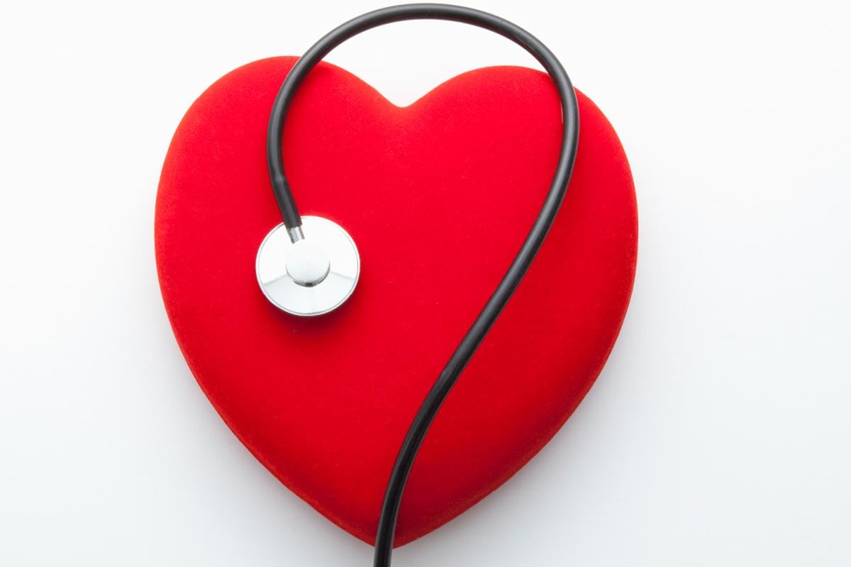 Stethoscope on top of red heart on white background