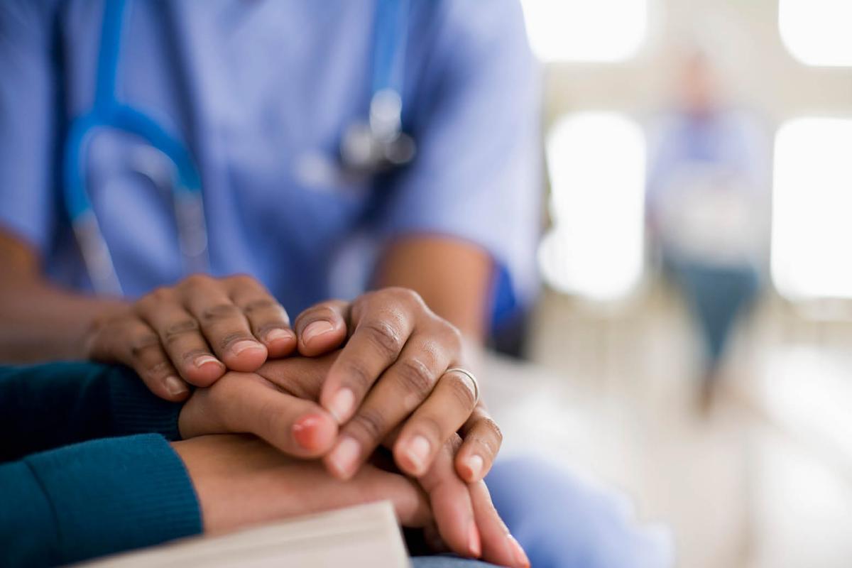 Physician clasping patient's hands in sympathy
