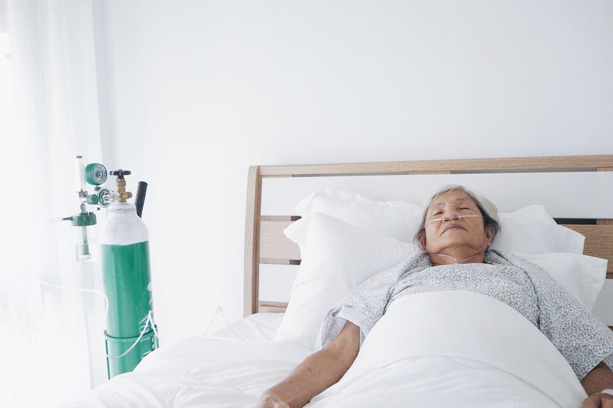 Woman in bed with an oxygen tank nearby