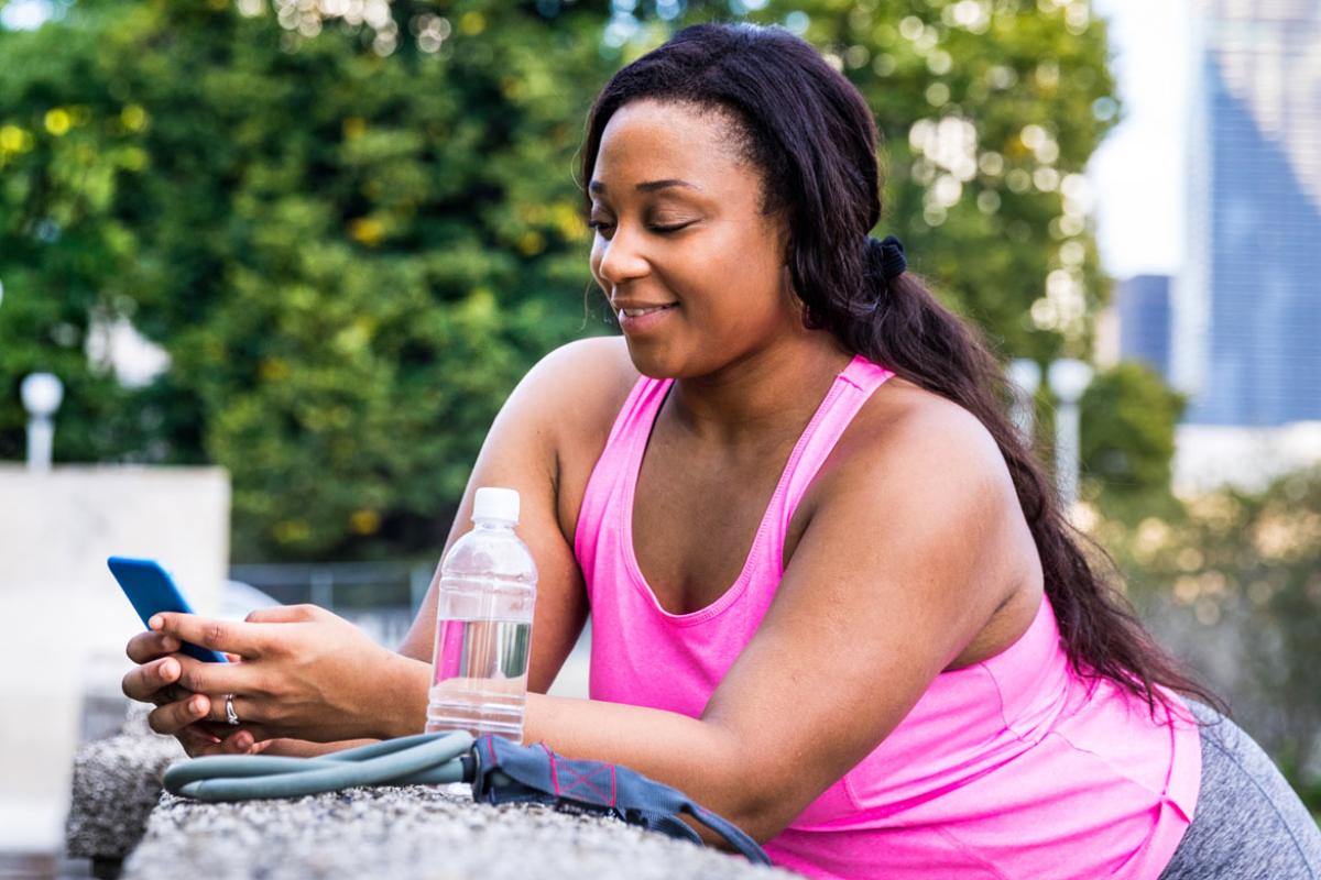 Woman in fitness clothes, looking at cell phone