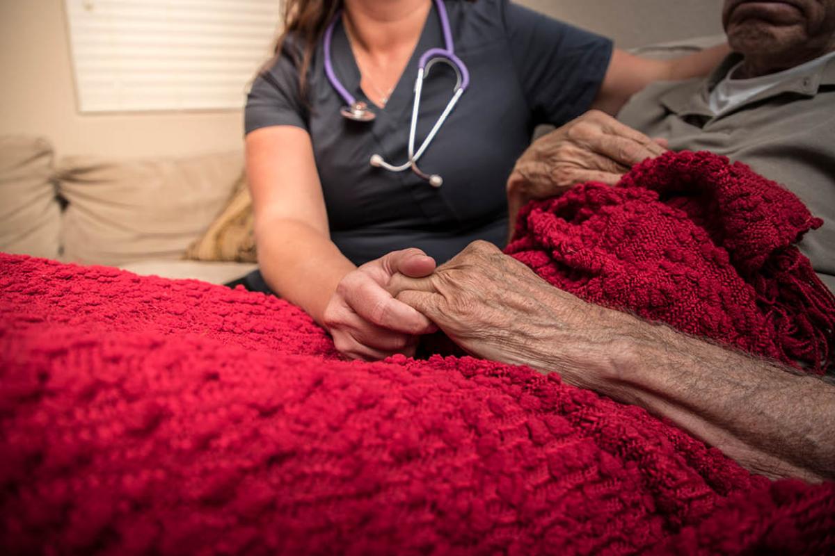 Health care professional and patient holding hands