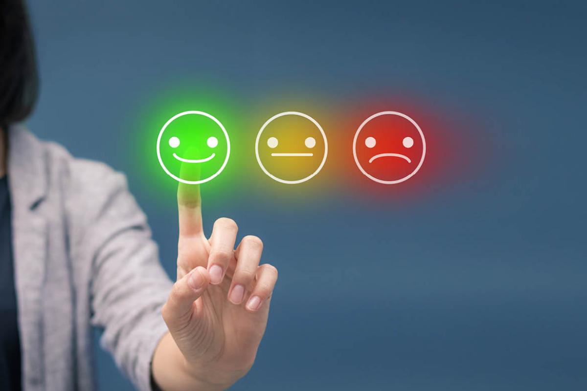 Person touching a screen of 'rate your satisfaction' smileys