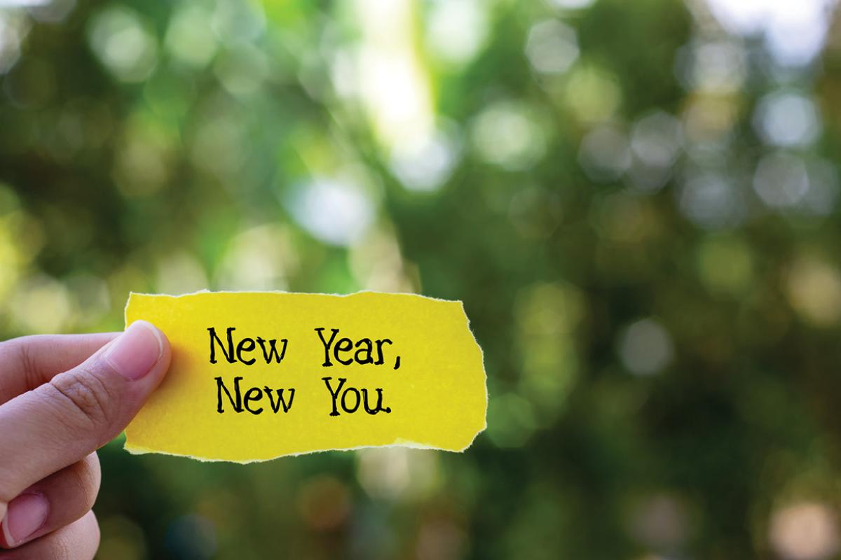 Hand holding a paper with the words New Year New You