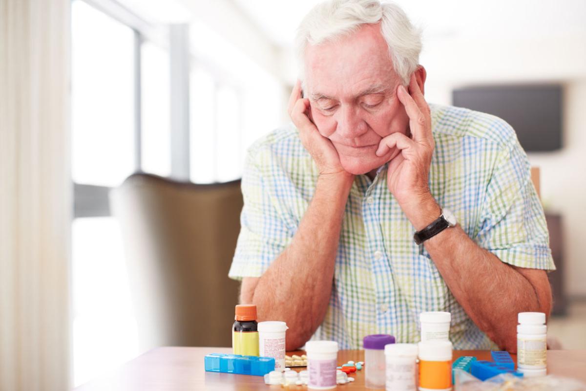 Elderly man looking at prescription bottles