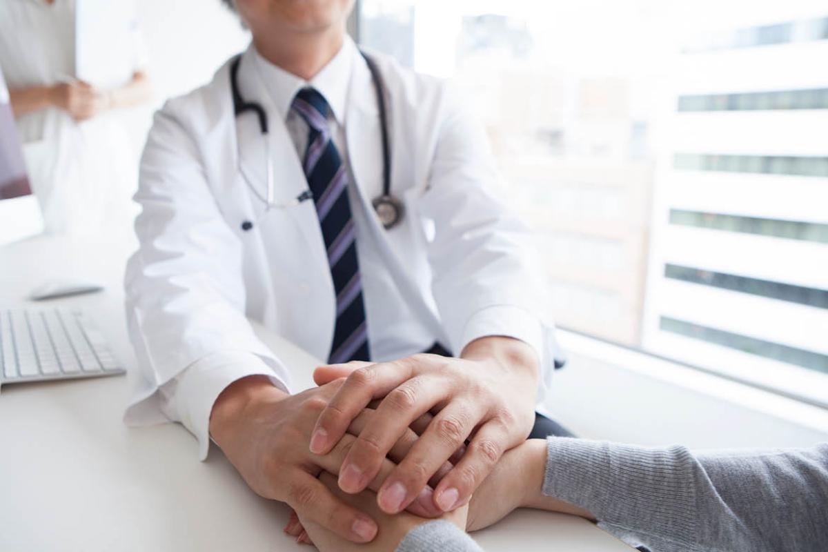 Physician and patient holding hands
