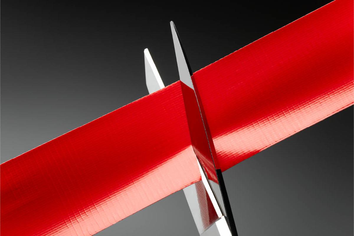 Scissors cutting a red ribbon or tape